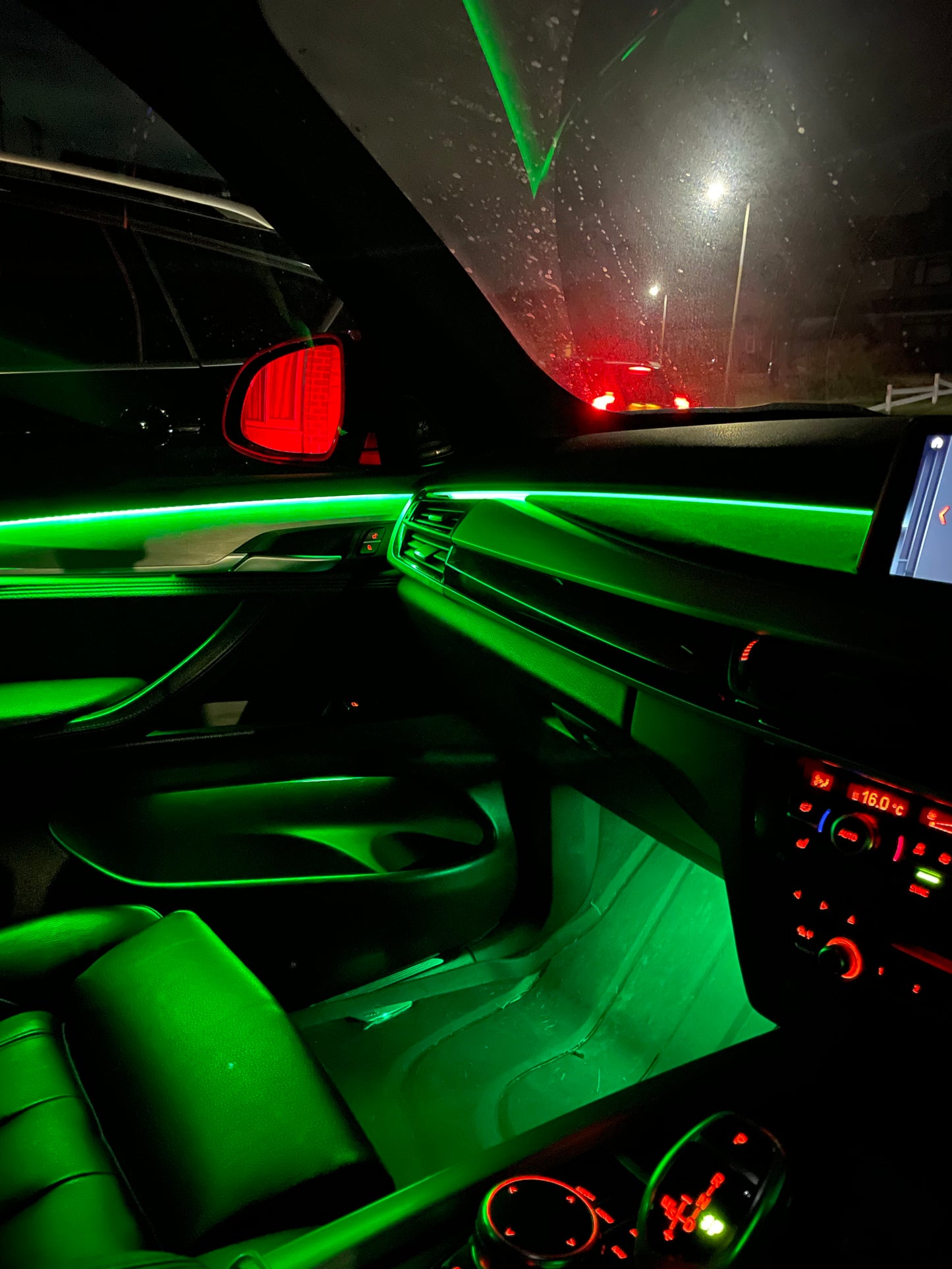 "Car interior with green LED ambient lighting installed along dashboard and door panels, showcasing a sleek and modern illuminated effect"