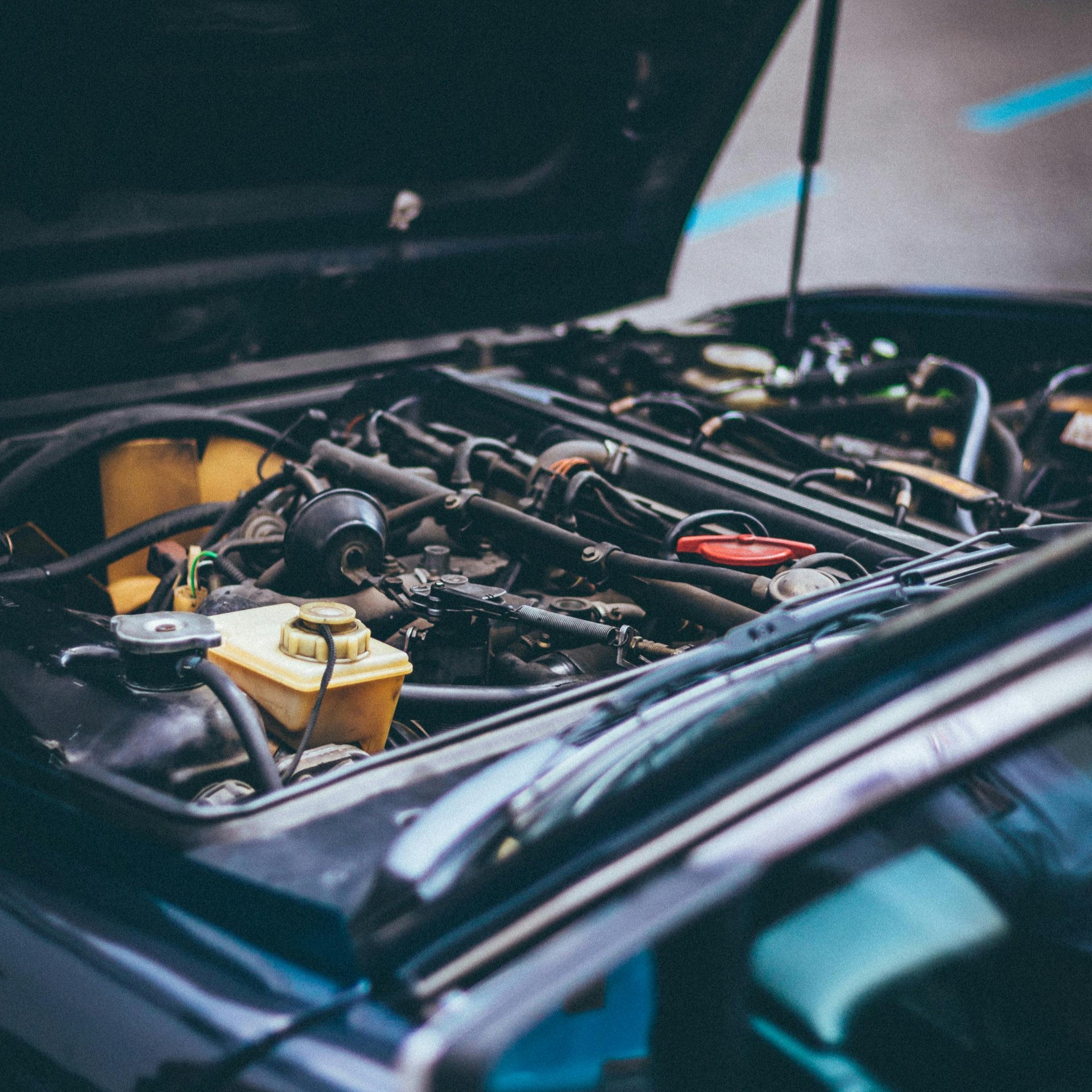 "Car engine bay with hood open, promoting professional installation services by in-house engineers"