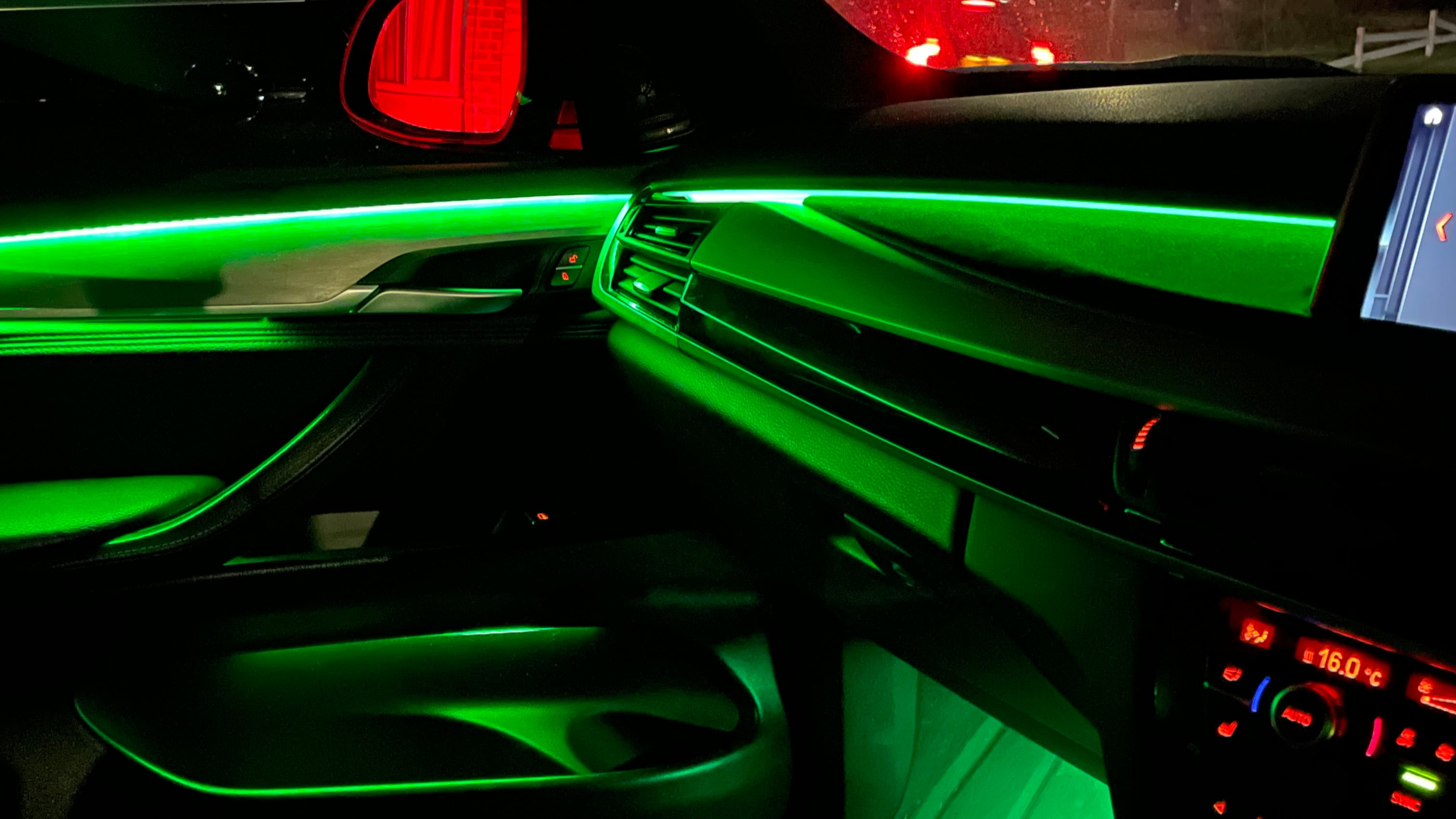 "Car interior with green LED ambient lighting installed along dashboard and door panels, showcasing a sleek and modern illuminated effect"